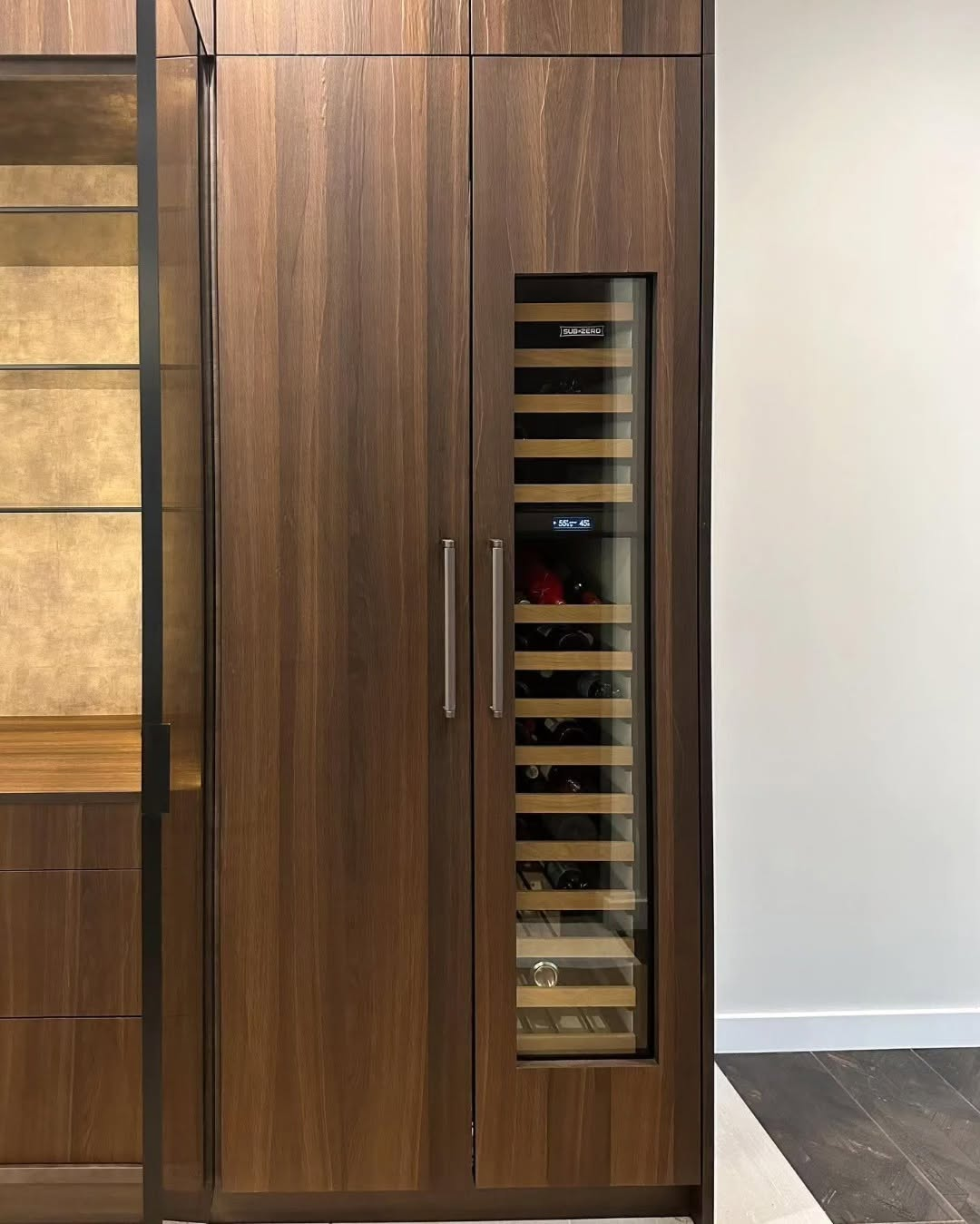 Custom millwork wine wall with brass-lit shelving